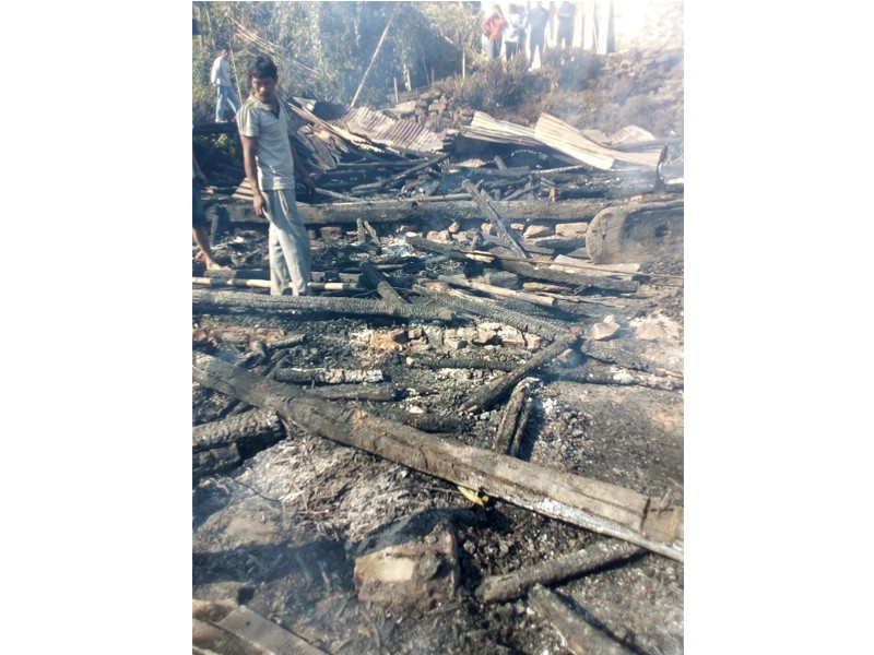 Villagers look on at the remnants of a house that was razed in a fire in Wakching village on November 8. (Morung Photo)